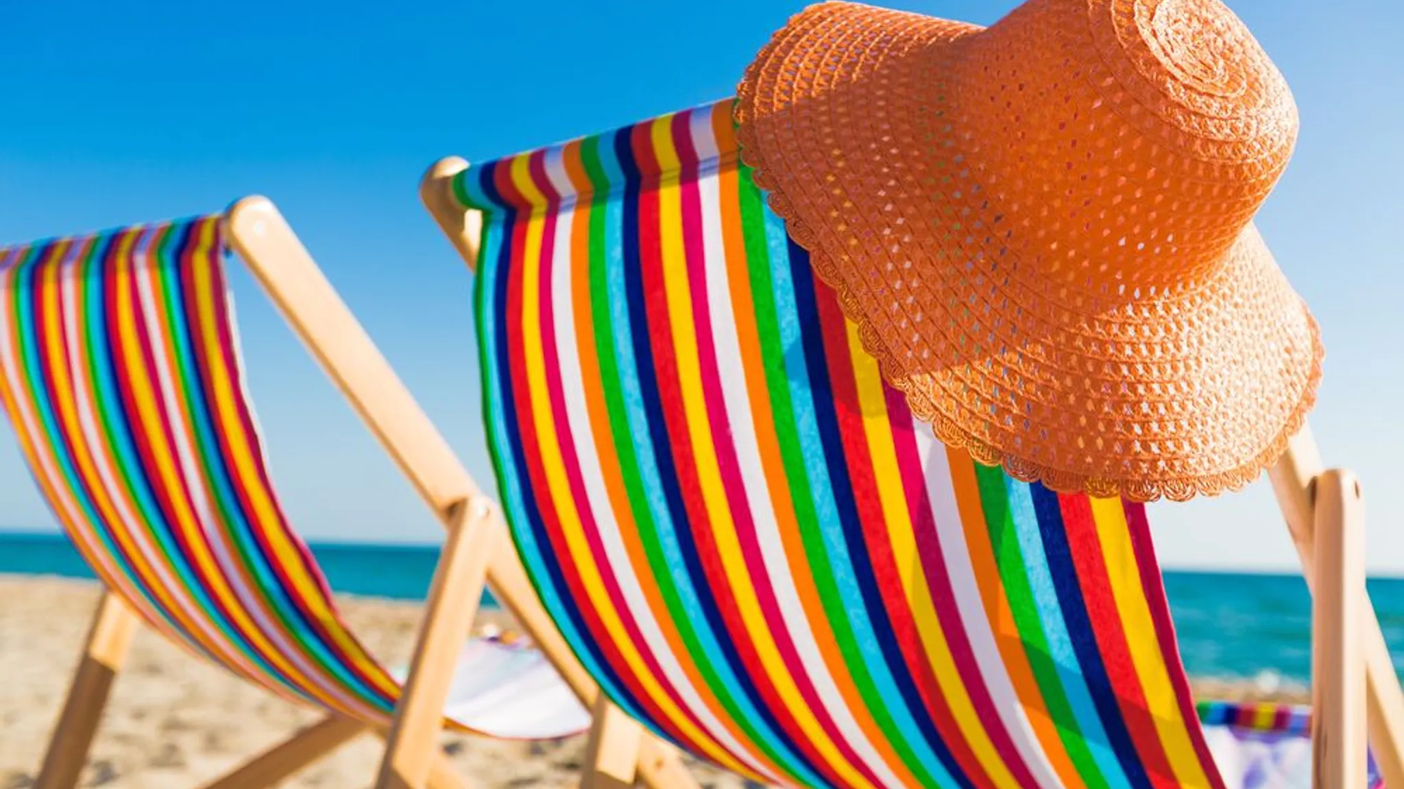 Oranje strandhoed aan gekleurde strandstoel op strand