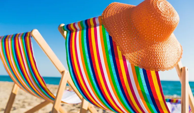 Oranje strandhoed aan gekleurde strandstoel op strand