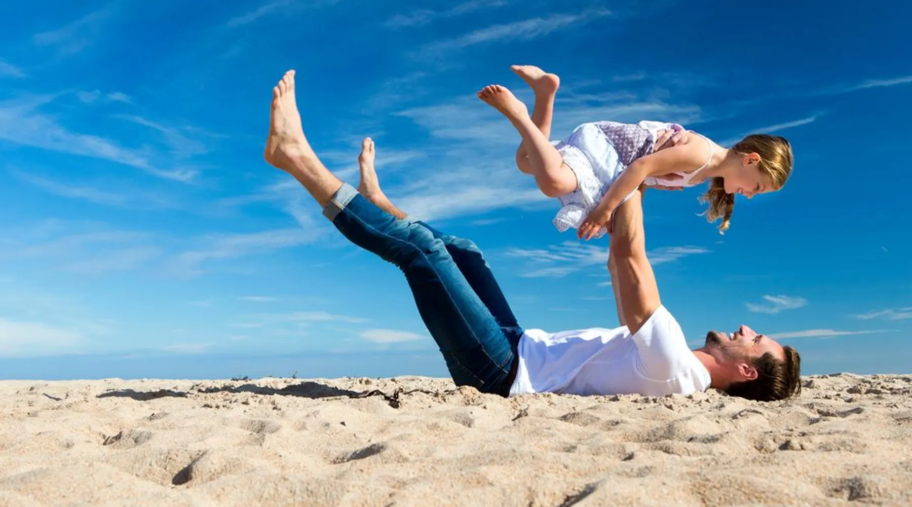 Père et fille jouant sur la plage en été