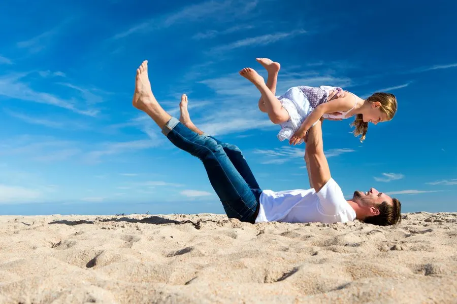 Vader met dochter spelend op het strand in de zomer