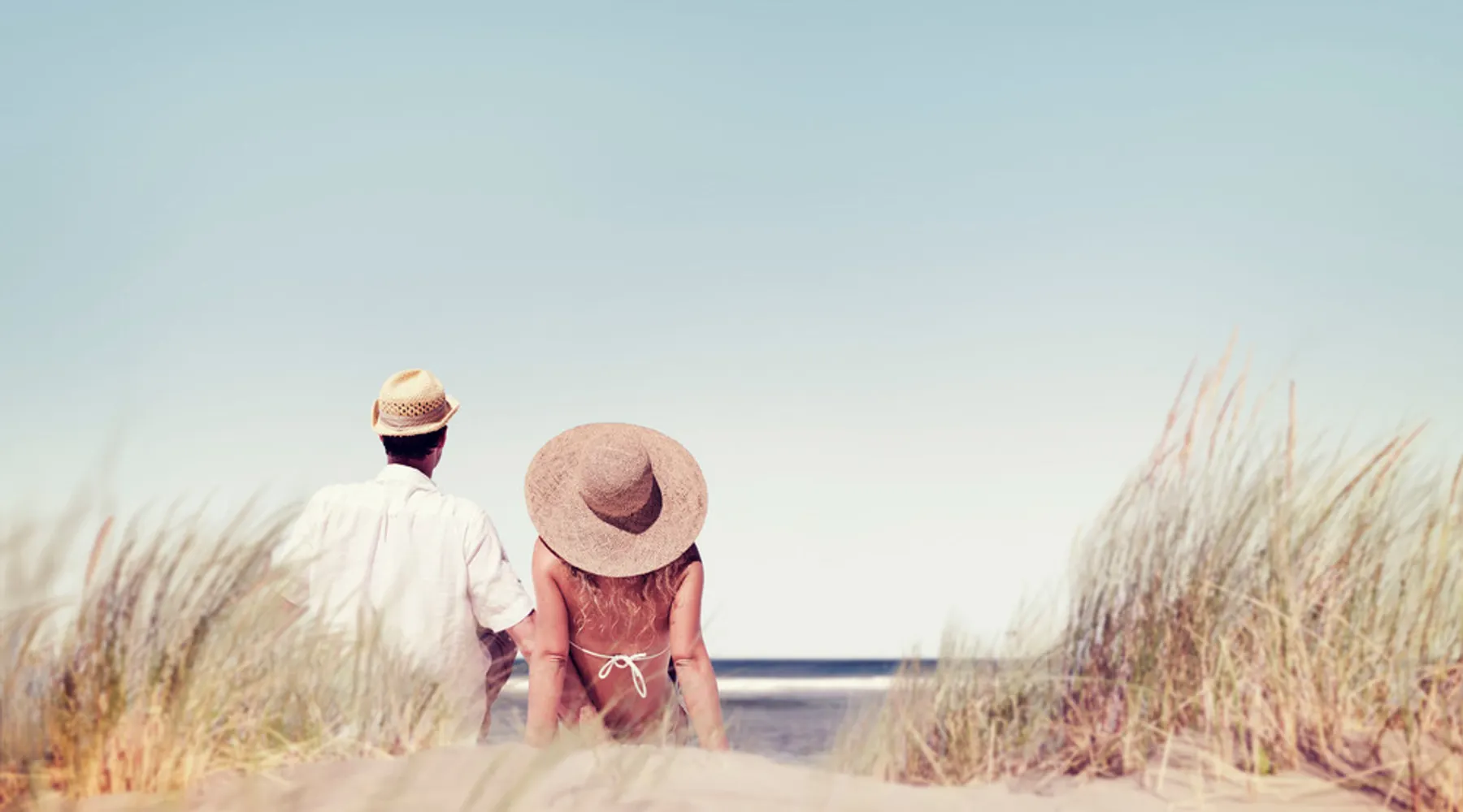 L'homme et la femme sont assis ensemble romantiquement dans les dunes sur la plage