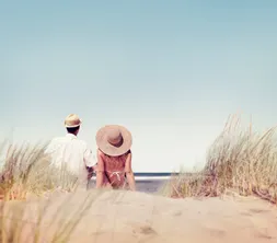 Man en vrouw zitten samen romantisch in de duinen aan het strand