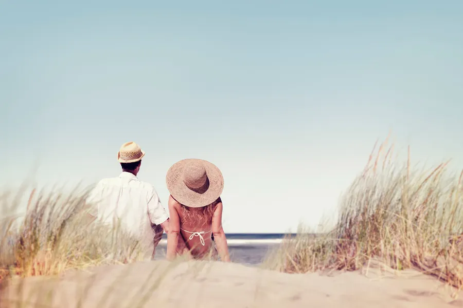 Man en vrouw zitten samen romantisch in de duinen aan het strand