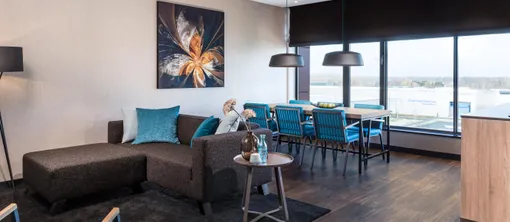 Woonkamer loft Van der Valk Hotel Veenendaal met bank, eettafel en uitzicht