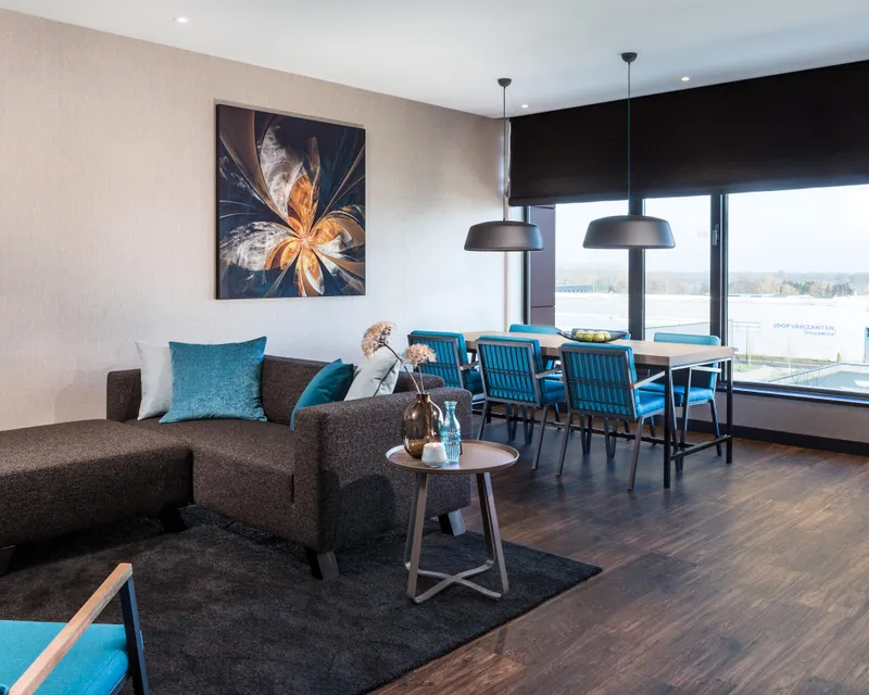 Woonkamer loft Van der Valk Hotel Veenendaal met bank, eettafel en uitzicht