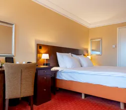 Schlafbereich und Schreibtisch in einem Standardzimmer mit Balkon