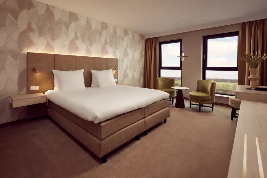 Tweepersoonsbed met comfortabel zithoekje in een moderne comfort hotelkamer van Van der Valk Hotel Gorinchem-A15