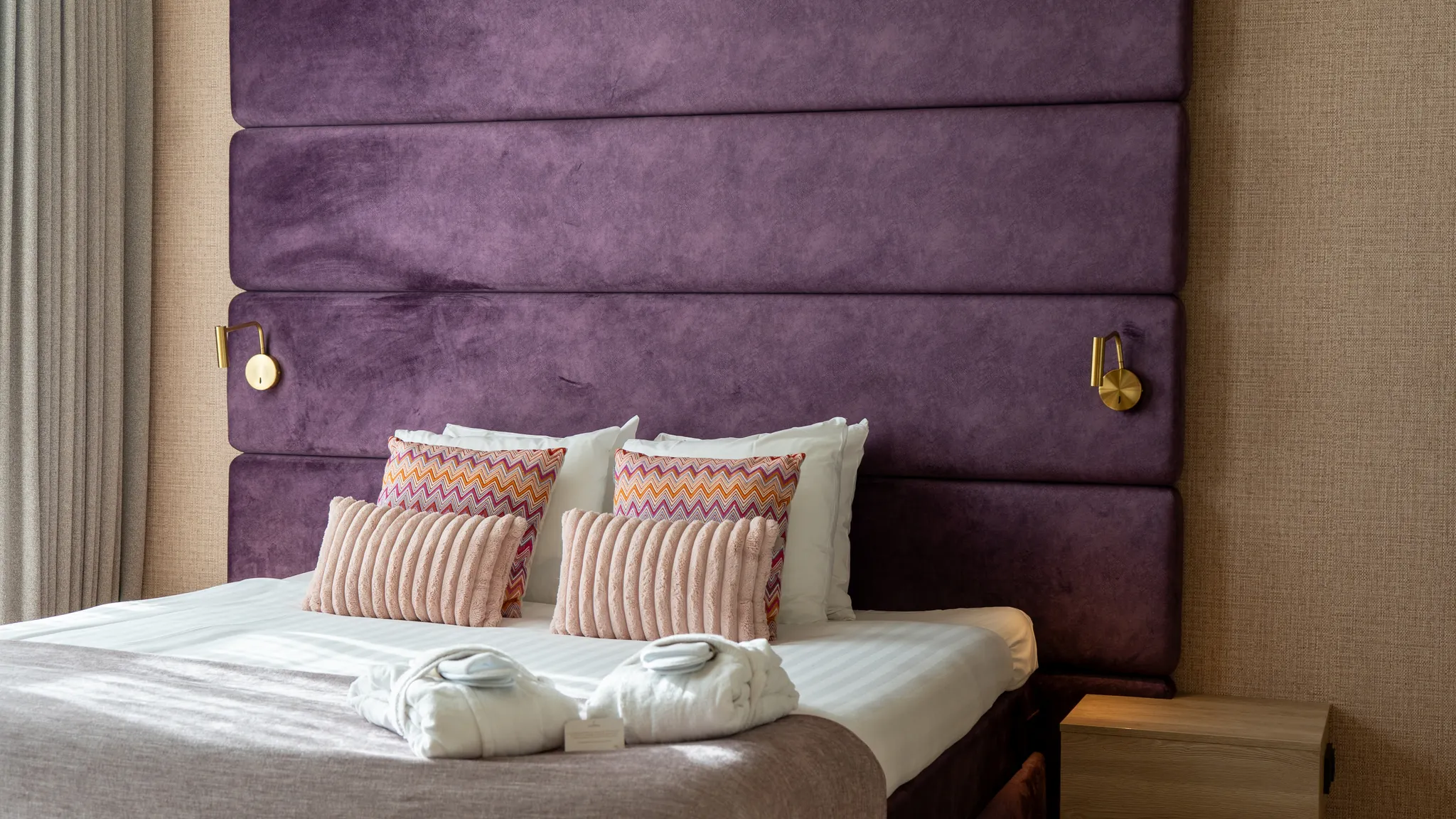 Lit fait avec goût et agrémenté de coussins décoratifs colorés dans la suite Purple Wellness