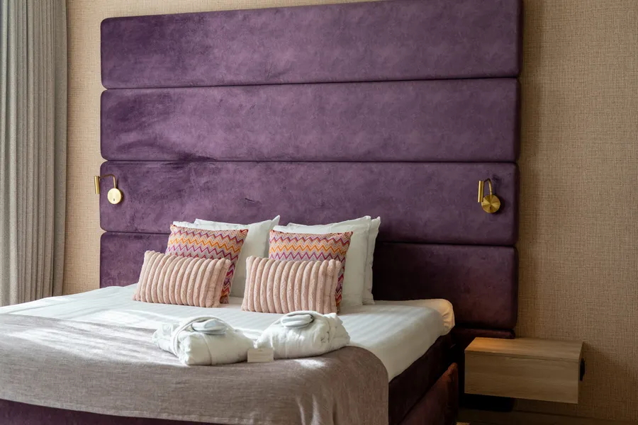 Sfeervol opgemaakt bed met kleurrijke sierkussens in de Wellness Suite Paars