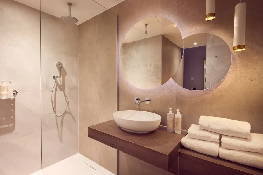 Moderne badkamer met regendouche, wastafel en ronde spiegels in Van der Valk Hotel Gorinchem-A15