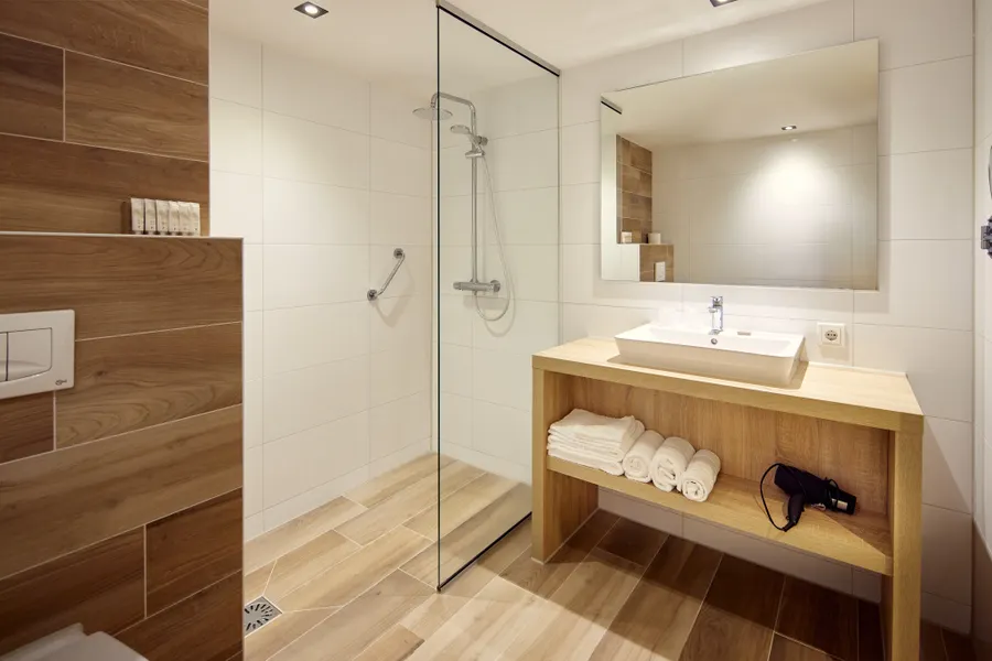 Houten badkamermeubel met wastafel, grote spiegel en zachte handdoeken in de hotelkamer