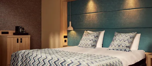 Komfortables Doppelbett mit luxuriösem Kopfteil im Superior Deluxe Hotelzimmer