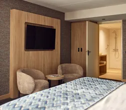 Sitzecke mit bequemen Sesseln und Flachbildfernseher im Superior Deluxe Hotelzimmer