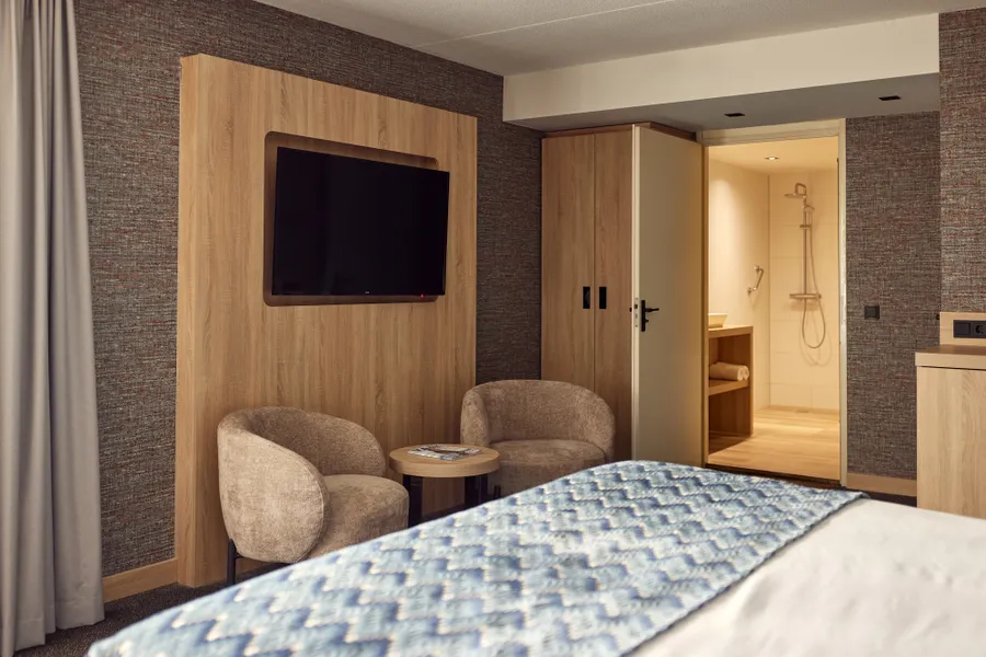 Zithoek met comfortabele fauteuils en flatscreen in de Superior Deluxe hotelkamer