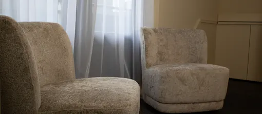 Comfortabele fauteuils bij het raam creëren een rustige zithoek in de hotelkamer