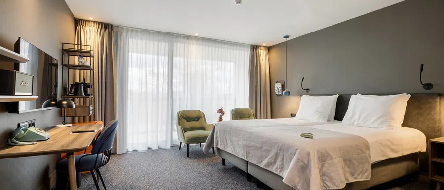 Modern eingerichtetes Superior Doppelzimmer mit einem komfortablen Doppelbett, großen Fenstern und einer Sitzecke