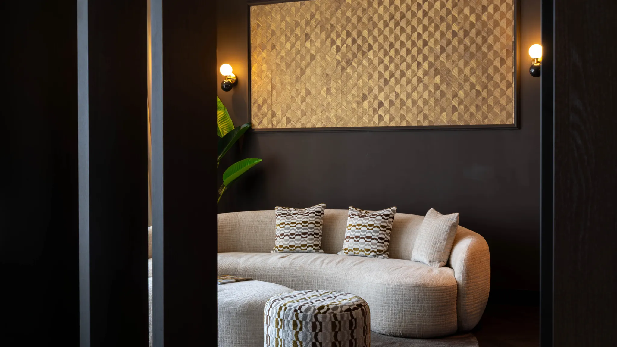 Marron Suite Van der Valk Nuland Sitzecke mit runder Couch und Hocker.