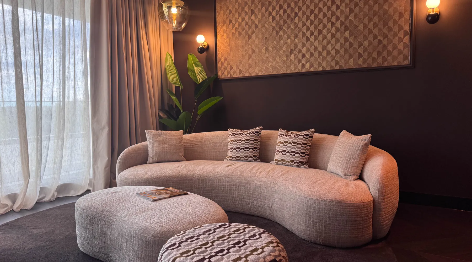 Marron Suite Van der Valk Nuland sitting area with round sofa and large windows.