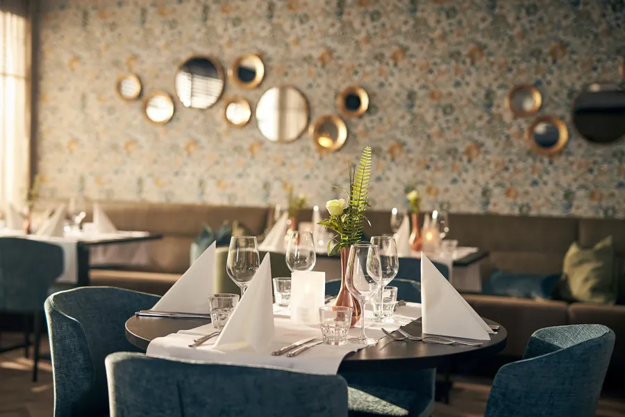 Sfeervol restaurantgedeelte met gedekte tafels en opvallende wanddecoratie, klaar voor het kerstdiner.