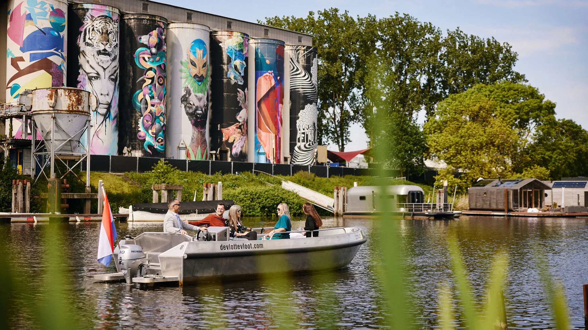 Een recreatiebootje vaart op het water langs de kleurrijk beschilderde silo's in de bruisende stad 's-Hertogenbosch.