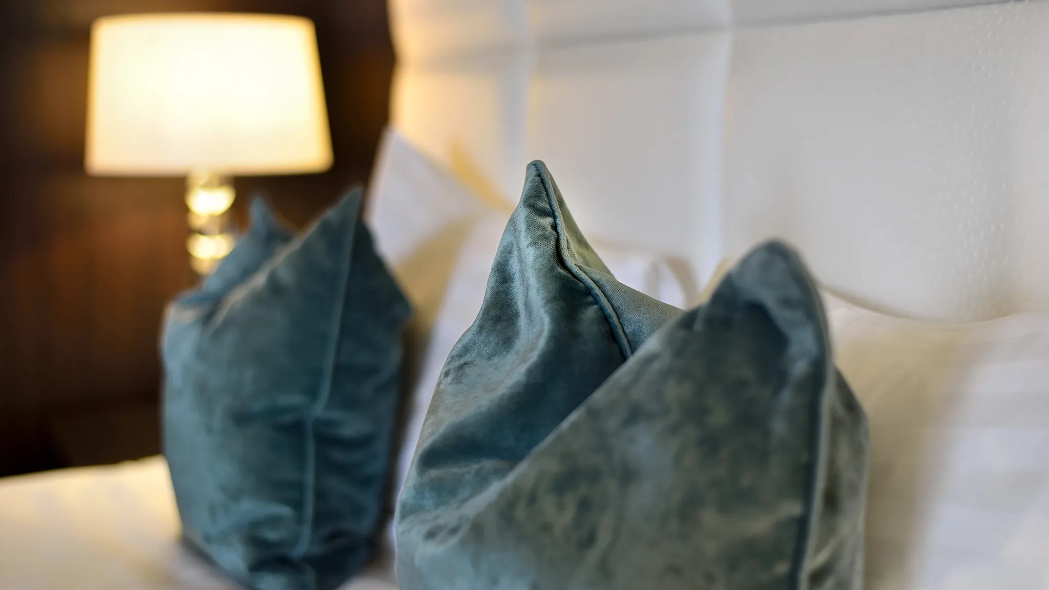 Detail van sfeervolle blauwe kussens op een comfortabel opgemaakt hotelbed voor een ontspannen zondagovernachting.