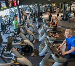 Gasten sporten actief op de cardio-apparatuur in de moderne fitnessruimte, één van de gratis sportfaciliteiten van het hotel.