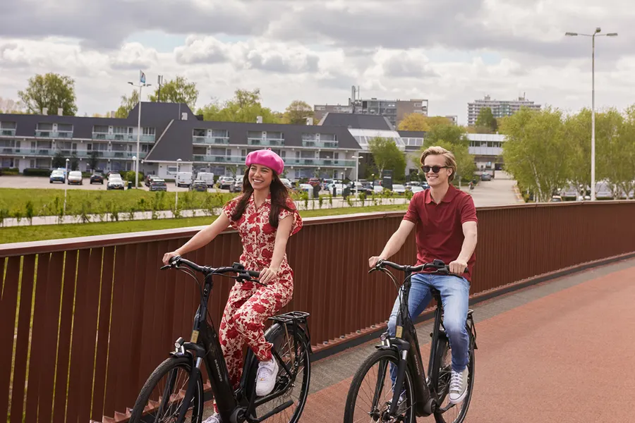 Een stel fietst ontspannen over de unieke Paleisbrug in 's-Hertogenbosch, een mooie manier om de stad en omgeving te ontdekken.