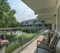 Sonniger Balkon eines Hotelzimmers mit Sitzgelegenheiten und Blick auf den grünen Innenhof.