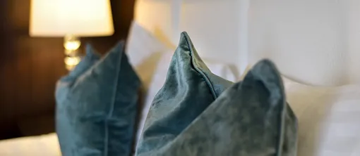 Detailansicht von luxuriösen Samtkissen auf einem ansprechend gemachten Bett für einen komfortablen und erholsamen Aufenthalt.