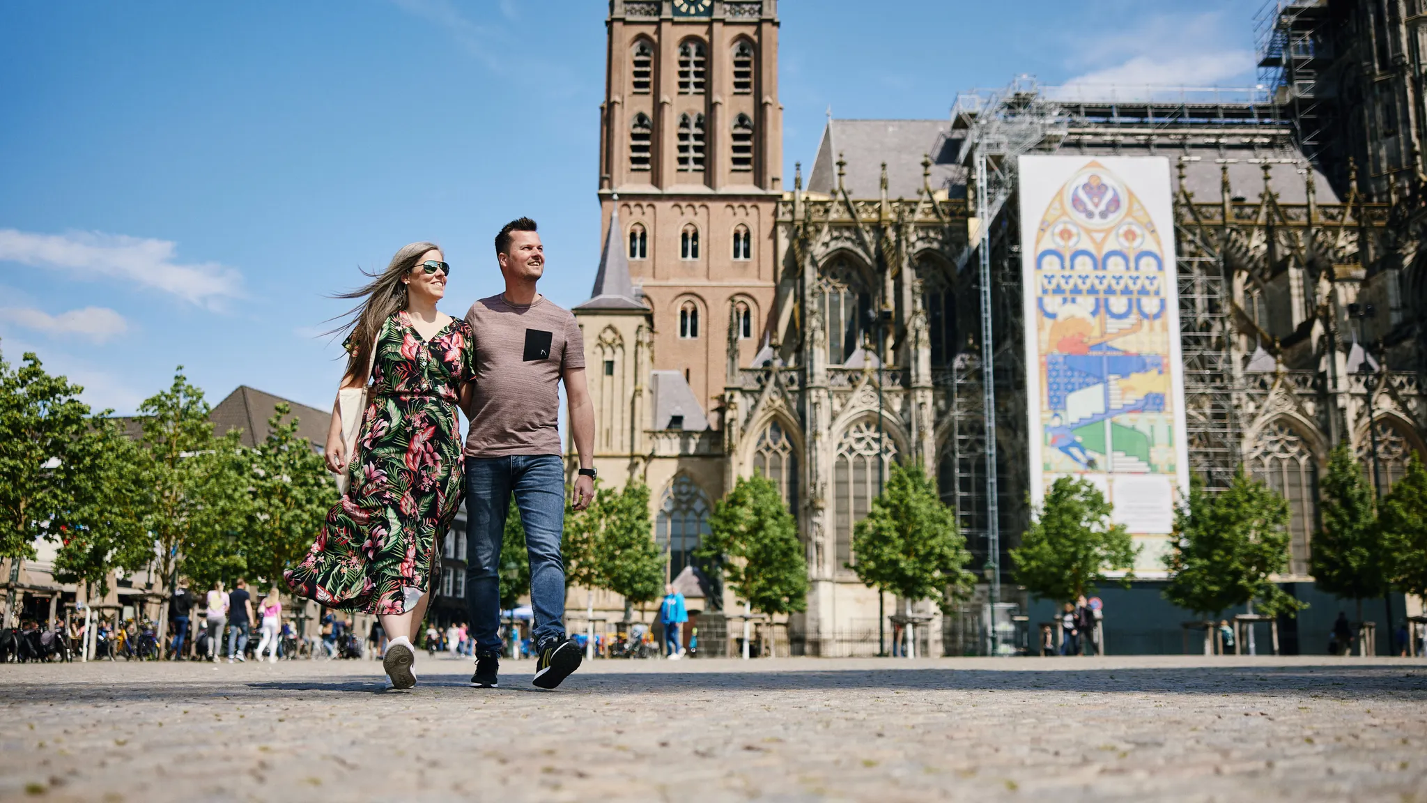 Ein spazierendes Paar entdeckt das historische Stadtzentrum von 's-Hertogenbosch mit der imposanten St.-Johannes-Kathedrale im Hintergrund.