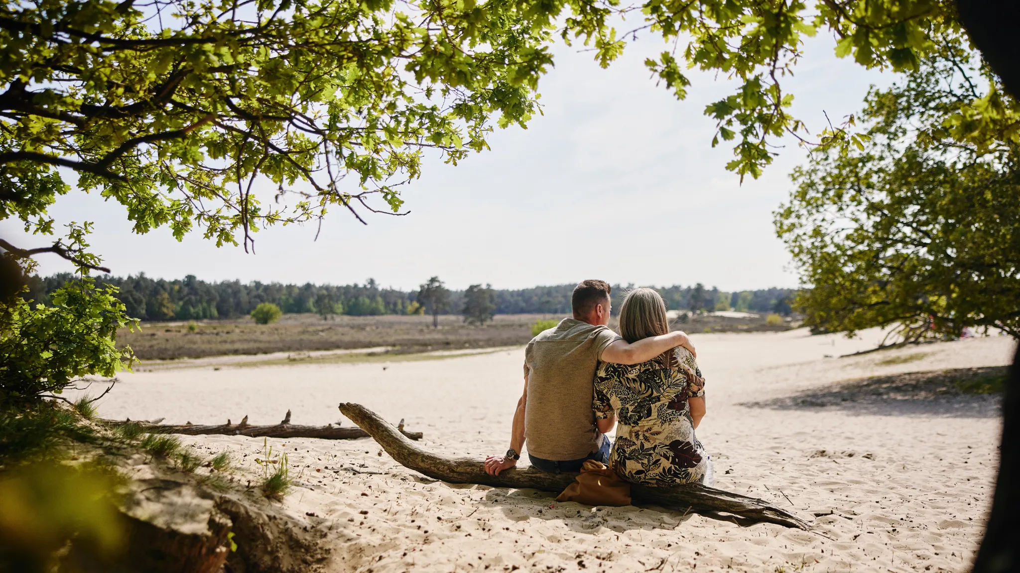 Ein Paar sitzt entspannt im Sand und blickt über die Natur, typisch für die nahegelegenen Loonse und Drunense Duinen.