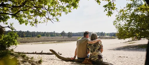 Ein Paar sitzt entspannt im Sand und blickt über die Natur, typisch für die nahegelegenen Loonse und Drunense Duinen.