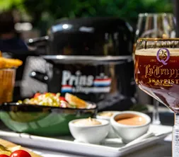Ein schmackhaftes und sommerliches Gericht mit frischen Miesmuscheln in einem traditionellen Muscheltopf, serviert mit Pommes frites und einem kalten Glas Bier.