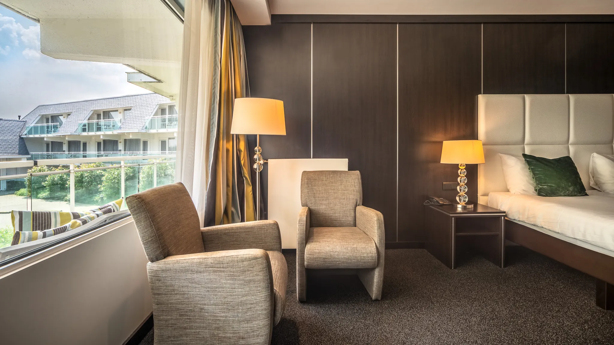 Gezellige zithoek in de Comfort Kamer met twee fauteuils, sfeerverlichting en een groot raam.