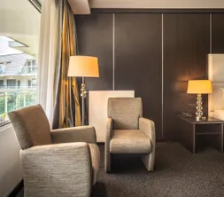 Gezellige zithoek in de Comfort Kamer met twee fauteuils, sfeerverlichting en een groot raam.