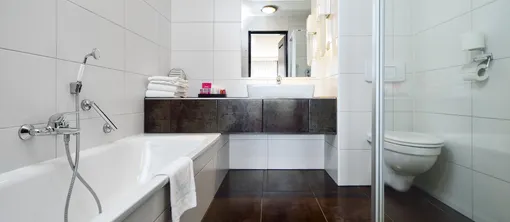 Moderne badkamer van de 3-persoonskamer, uitgerust met een ligbad, donker wastafelmeubel en een glazen inloopdouche